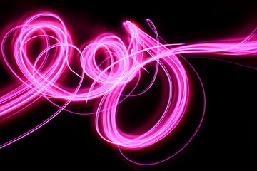 Light painting, long exposure photography, vibrant neon pink swirls of color against a black background