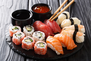 Uramaki and nigiri sushi served in black plate closeup. horizontal