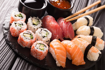 japanese seafood, restaurant menu photo. great colorful set of fresh sushi rolls with salmon, tuna, nigiri and maki served in black plate close-up. Horizontal