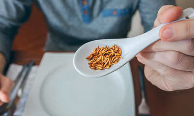 Man showing a spoonful of worms ready to eat
