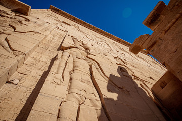 Philae Temple facade with giant rock carved statue of Isis Goddess and hieroglyphs