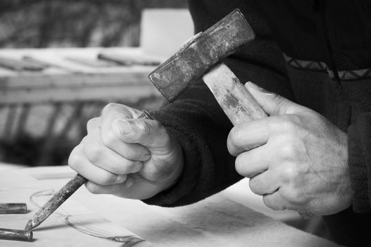 Craftsman hands, working the stone with his tools and blurred background