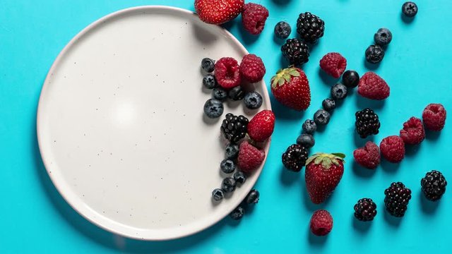 Top view of a plate with variety of forest fruits, berries and hearts on a blue background, stop motion animation, Saint Valentines day
