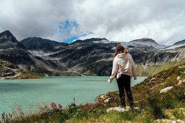 Young woman looking at mountain lake in the Alps