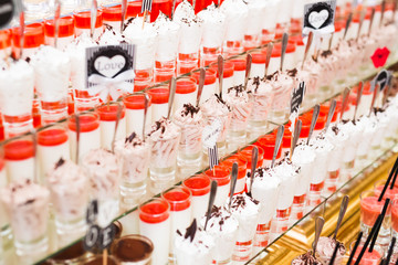 Delicious and tasty dessert table with cupcakes shots at reception closeup