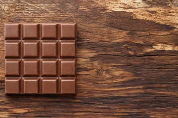 Milk chocolate bar on wooden background