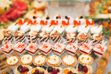 Delicious and tasty dessert table with cupcakes shots at reception closeup