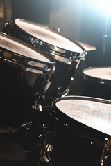 Fototapeta na wymiar Closeup view of a drum set in a dark studio. Black drum barrels with chrome trim. The concept of live performances