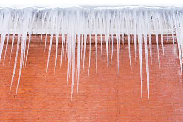 Long pretty icicles on brick wall background