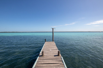 Fototapeta na wymiar wooden jetty for boats on a blue and blue crystalline Caribbean sea. Caribbean vacation with a dedicated boat dock