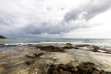 Caribbean bay with rocks, sandy beach and coral reef. clear sea of a coral reef beach with beach and clouds on the horizon and waves crashing on the shore