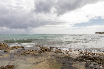 Caribbean bay with rocks, sandy beach and coral reef. clear sea of a coral reef beach with beach and clouds on the horizon and waves crashing on the shore