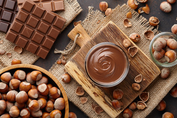 Chocolate spread, nuts and chocolate bars on table