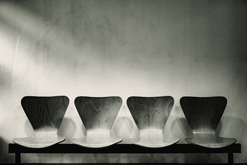 Waiting room with empty wooden chairs, concept of waiting and passage of time, black and white...