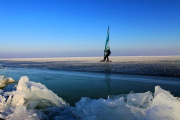 eissurfen auf zugefrorenem see im winter/sport am eis, abendliche stimmung am neusiedlersee in österreich/segel, himmel, schnee, alleine dahin gleitend mit blick auf die weite des horizonts