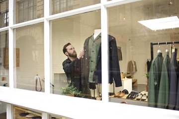 A proud shop owner dressing a mannequin