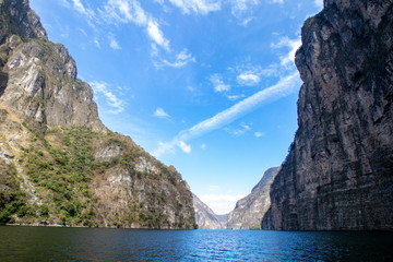 Obraz premium river in a canyon with high walls and florid green vegetation. walls that converge at a point in a canyon