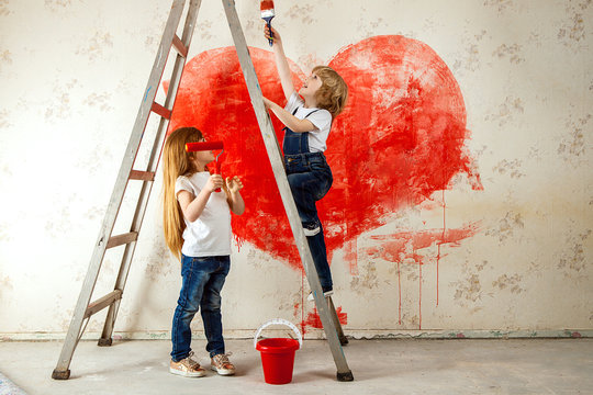 boy and a girl in jeans and a white T-shirt, look at each other, with a paintbrush and a bucket stand on a ladder paint the wall in red, a big heart