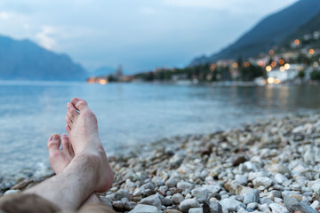 Man is sitting on the beach and enjoying the view over a lake, evening