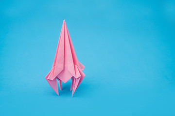 rocket from paper of origami on a blue background - obrazy, fototapety, plakaty
