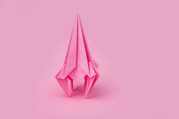 rocket from paper of origami on a pink background
