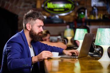 Man bearded businessman sit pub with laptop and cup of coffee. Manager work online while enjoy coffee. Online job. Hipster freelancer work online blog notebook. Surfing internet. Freelance benefit
