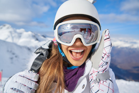 Portrait of beautiful woman with ski and ski suit in winter mountain.