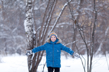 Fototapeta na wymiar Portrait of cheerful happy boy playing in winter park