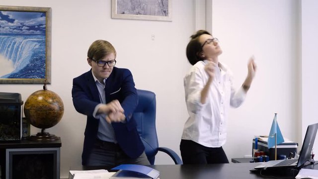 Workers dancing in office. Man and woman happily dance because of success in business or end of working day in office. Colleagues at work happily dance
