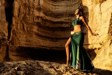 Young girl dancing to the famous arabic dance, belly dance with canyons of Namibe desert in...