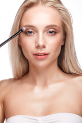 Naklejka premium Beautiful young girl with a light natural make-up,eye shadow brush and nude manicure. Beauty face.
