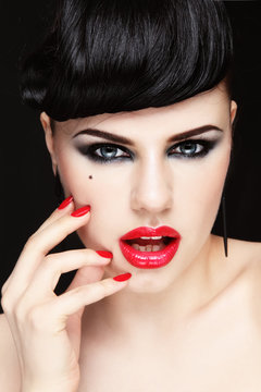 Portrait of young beautiful brunette with smokey eye make-up and red lips