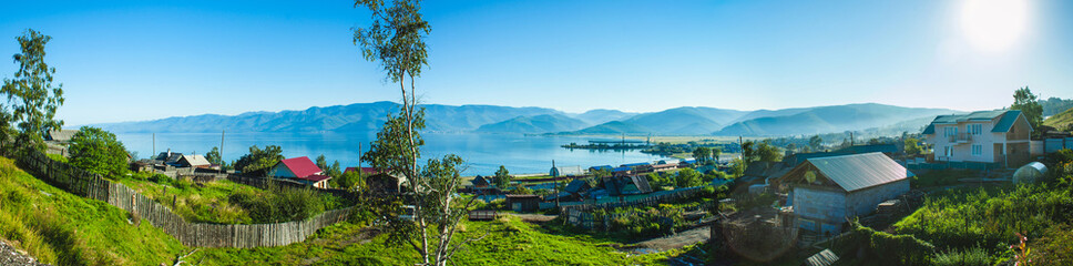 a panoramic view on a russian siberian village on the coast of the Baikal lake by sunny summer day - obrazy, fototapety, plakaty