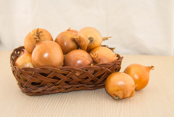 Obraz na płótnie Canvas Onions in a basket on a wooden base.