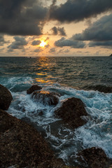 waves striking at the rocks of Kata beach on the Phuket island of Thailand at sunset