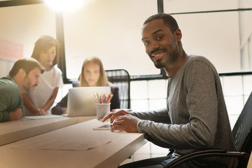 Attractive black man working in modern office space with co workers