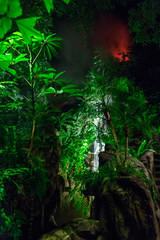 a waterfall and a vulcan in the jungles at night