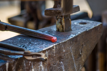 blacksmith performs the forging of hot glowing horseshoe on the anvil