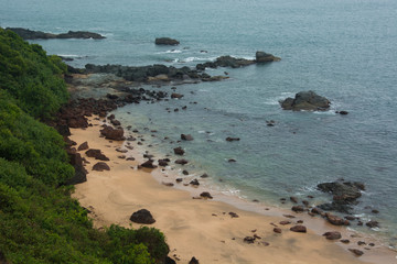A cliff top view of Cola Beach in Goa on a cloudy day