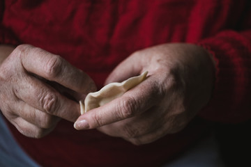 Homemade food - hands of a woman making traditional Polish pierogi. Soft moody tones.