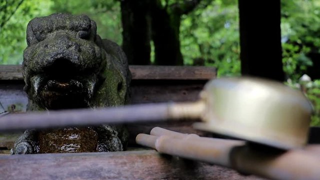 Change focusing at a ladle at the well with a water spout, shrine at Osaka castle area, Japan