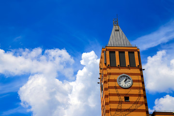 Fototapeta na wymiar Skyscraper with an orange brick clock tower against the blue sky with beautiful clouds. Architecture of Dnipro city, Dnepropetrovsk, Ukraine
