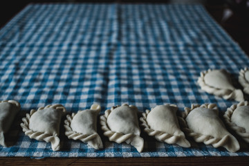 Homemade food - making traditional Polish pierogi. Dumplings laying on a kitchen cloth. Soft moody tones.