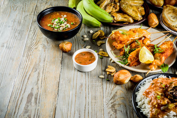 West african food concept. Traditional Wset African dishes assortment - peanut soup, jollof rice, grilled chicken wings, dry fried bananas plantains, nigerian chicken kebabs, meat pies, top view
