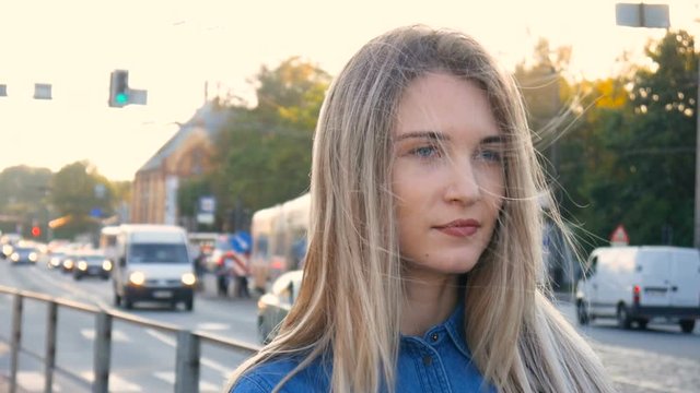 Pretty girl with beautiful blue eyes and long hair wainting for someone on a busy city street