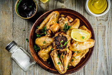 Grilled bbq chicken wings with sauces and spices, wooden background copy space top view