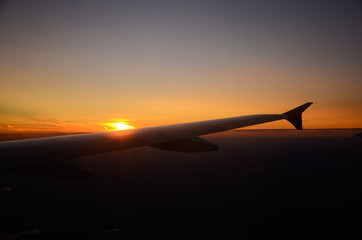 Airplane flying above clouds at sunrise. Aerial window view © buharina