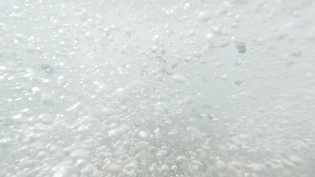 The sea surf fires pebbles in different directions. The video was shot under the water