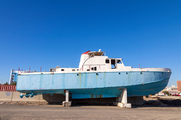 Old abandoned wrecked speed boat at ship or boat graveyard. Lots of different dry docked,...
