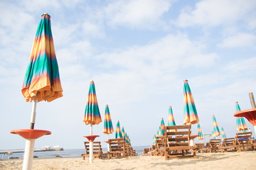 Aerial view to sandy beach of Adriatic sea in Albania, full of umbrellas and sunbeds, Port of Durres in horizon.